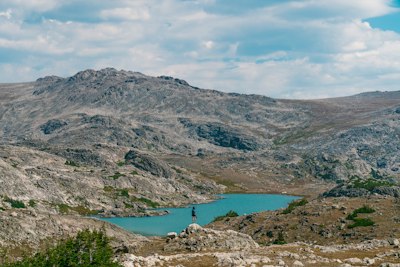 person standing on rock near lake during daytime