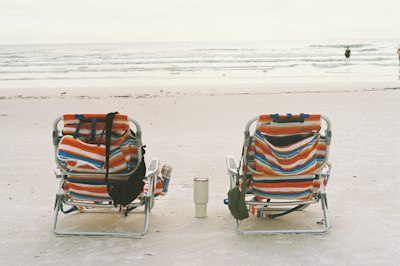 A couple of chairs sitting on top of a sandy beach