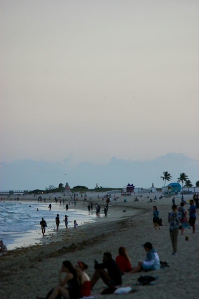 a group of people sitting on top of a sandy beach