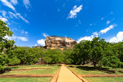 A path leading toward the Sigiriya rock fortress in Sri Lanka under a blue sky