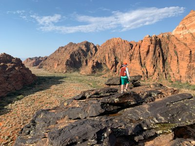 woman in teal tank top and blue denim jeans standing on rocky mountain during daytime