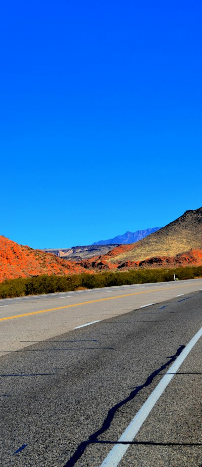 an empty highway with mountains in the background