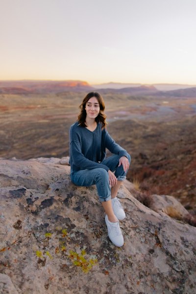 woman in blue denim jacket sitting on rock during daytime