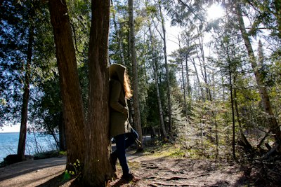 woman in green jacket and black pants walking on forest during daytime