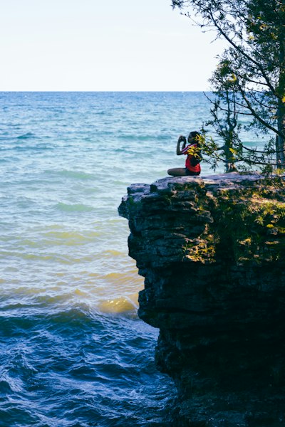 a person taking a picture of the ocean from a cliff
