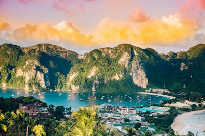 Boats in a bay on Phi Phi Island below green mountains under golden clouds