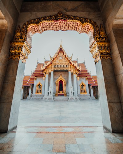 The Wat Benchamabophit temple framed by an ornate marble archway in Bangkok, Thailand