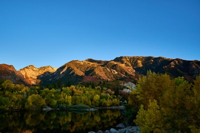 a lake surrounded by mountains with trees in the foreground