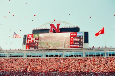 Fans celebrate at a football stadium with scoreboards