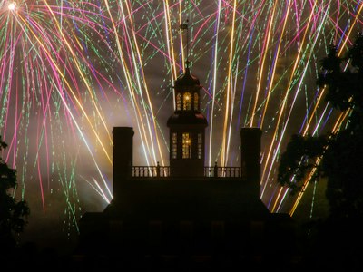 a building with a clock tower and fireworks in the sky