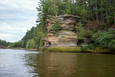 a rocky cliff with trees and water below